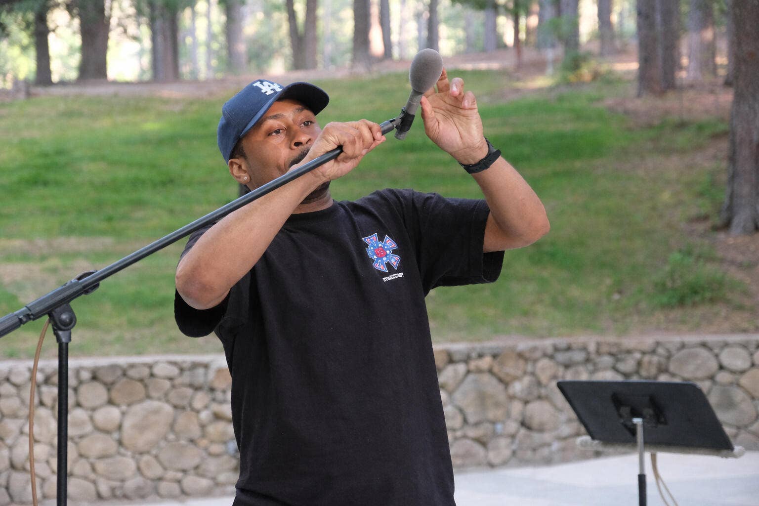 A Workforce Development Program participant sets up a microphone outdoors. 