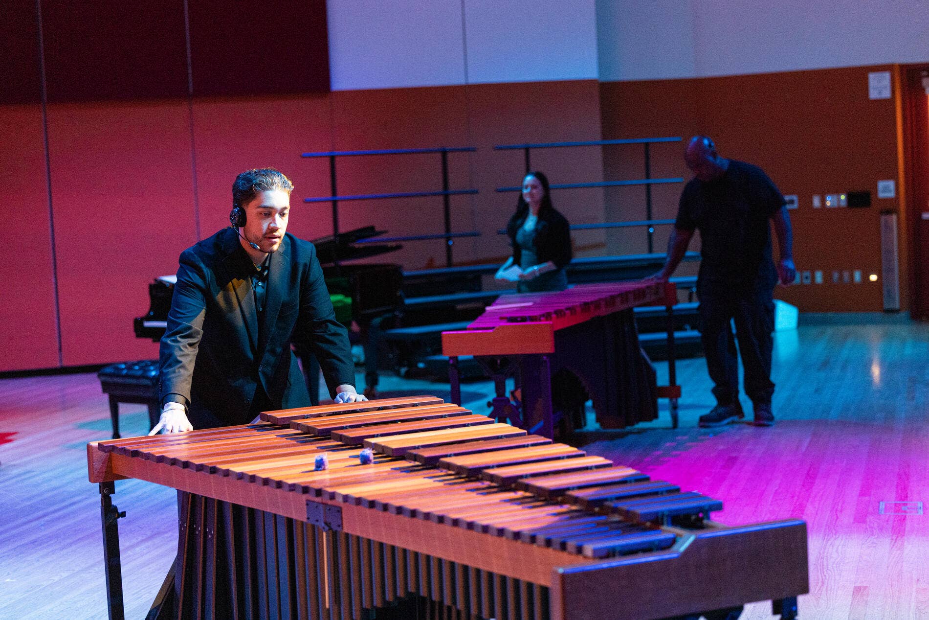 A Workforce Development Program participant moves a xylophone on stage during setup for a performance.