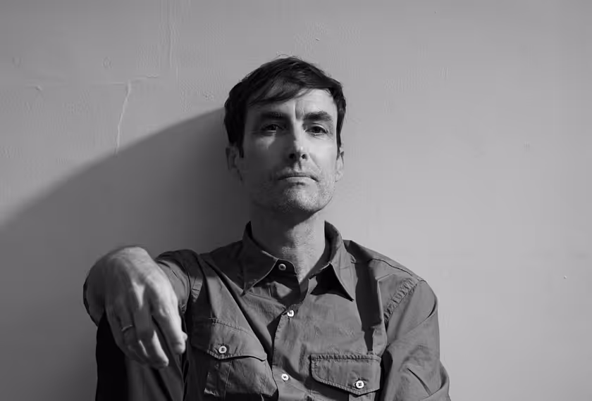 black and white portrait of man in button down against concrete wall