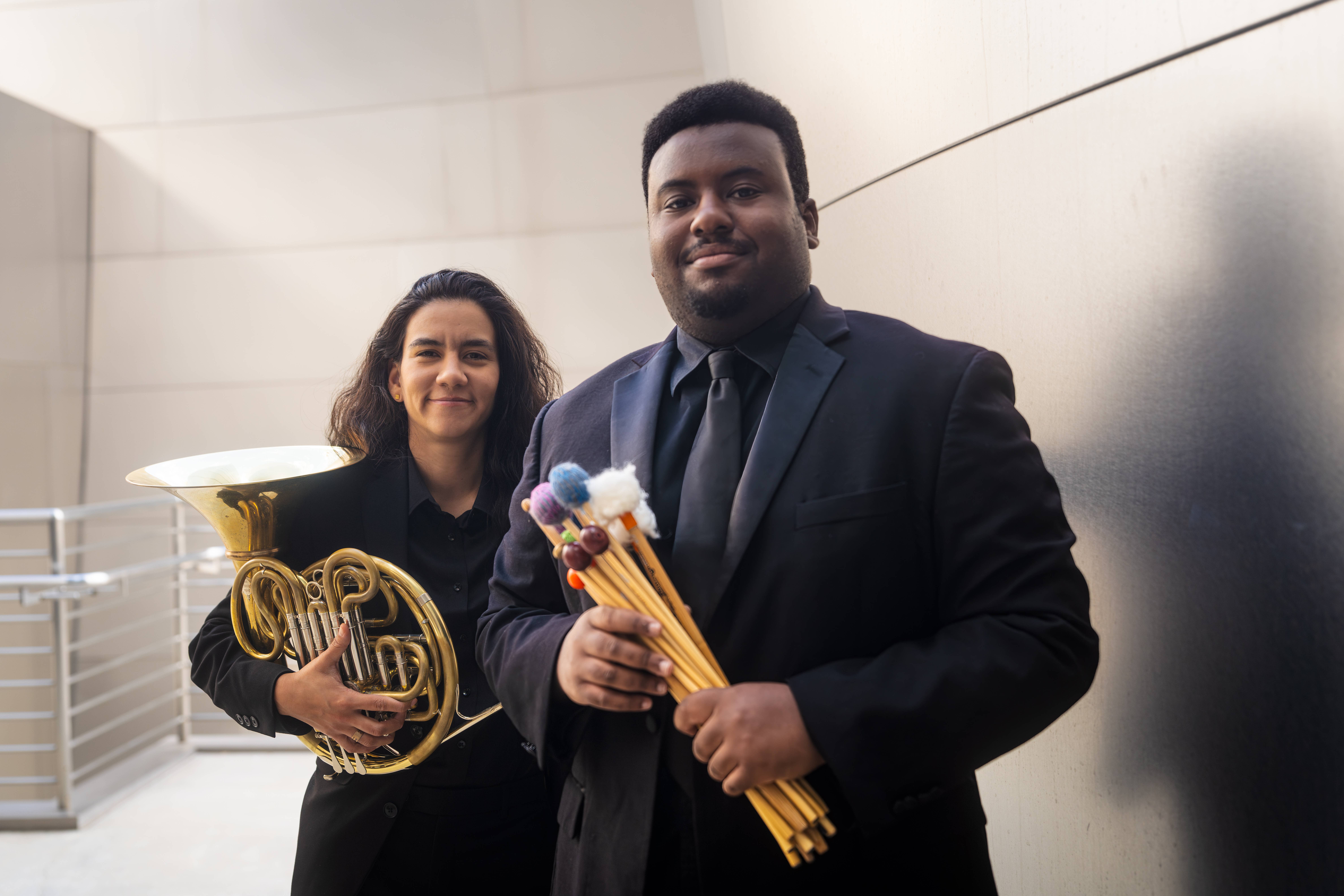Percussionist Jeremy Davis and French Horn player Elizabeth Montero stand side-by-side outside at the Walt Disney Concert Hall.