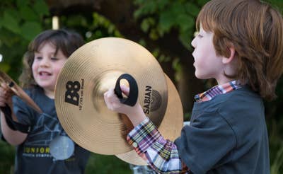 Dos niños al aire libre: uno sostiene un gran disco con la inscripción «B8», parecido a un platillo, mientras el otro sonríe a su lado.
