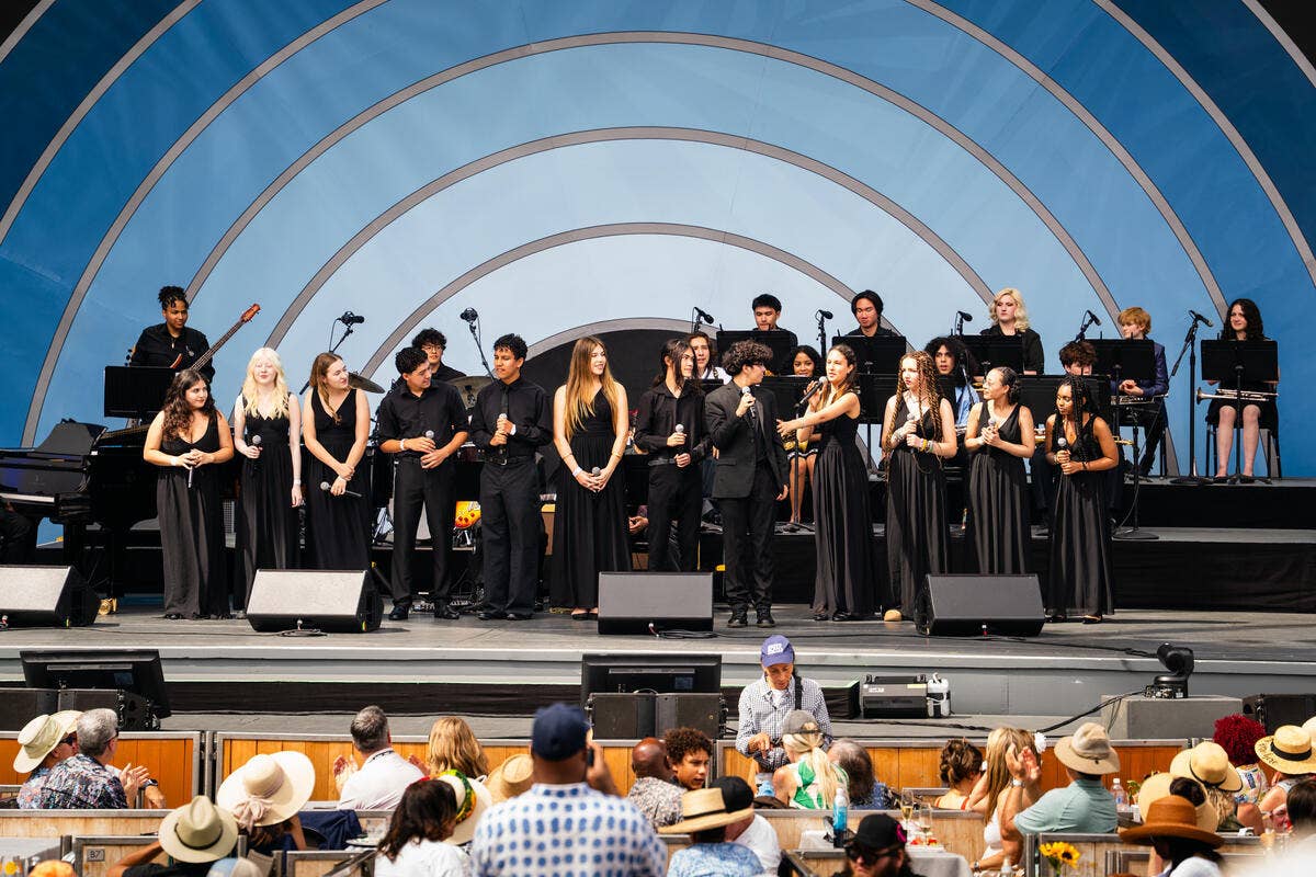 Awards ceremony on stage with performers holding trophies, microphones, and an audience seated in front of them.