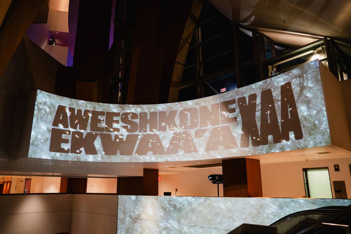 Indoor stage with large screen showing banner with text under warm lighting
