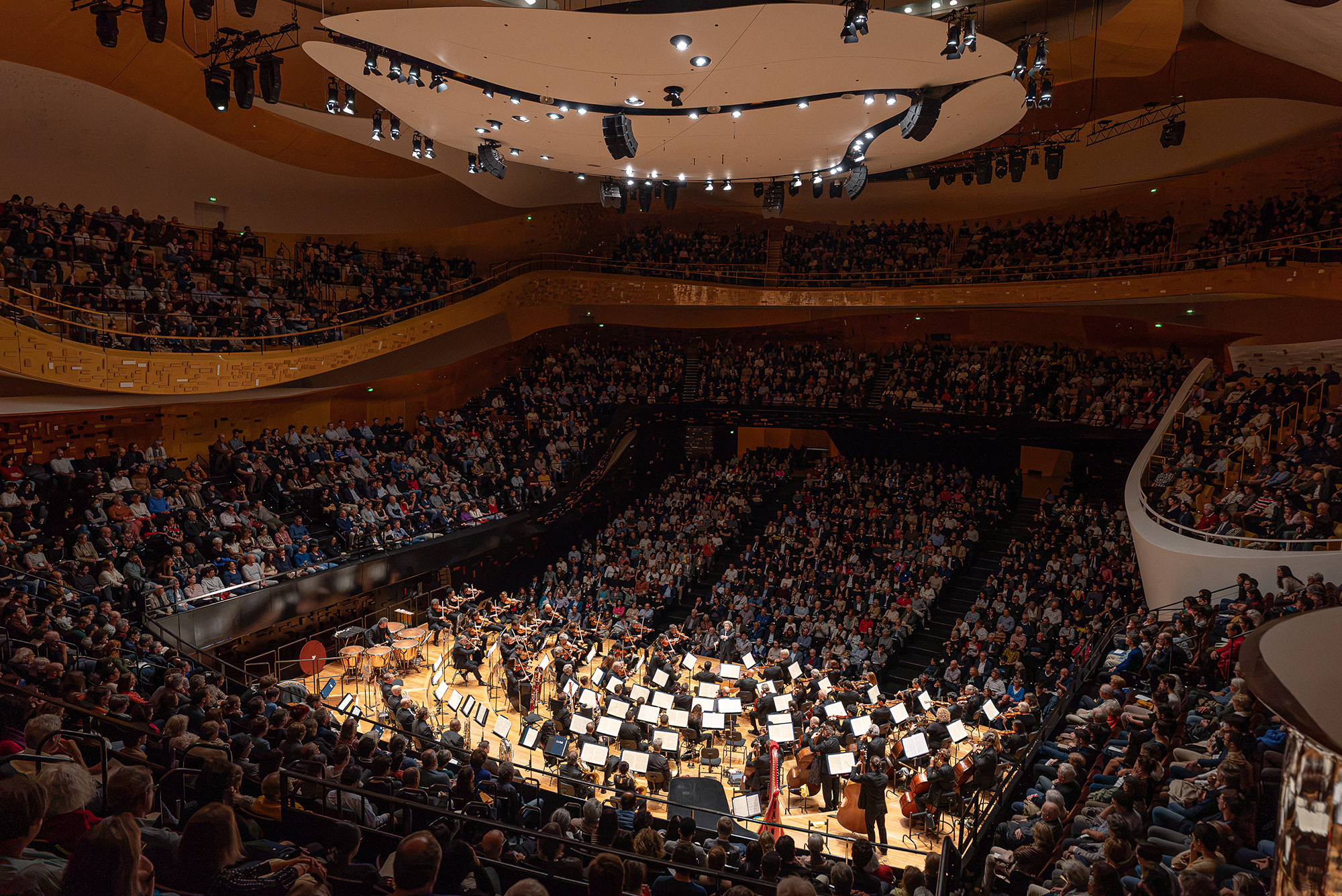 The orchestra playing on stage to a full audience during a performance.