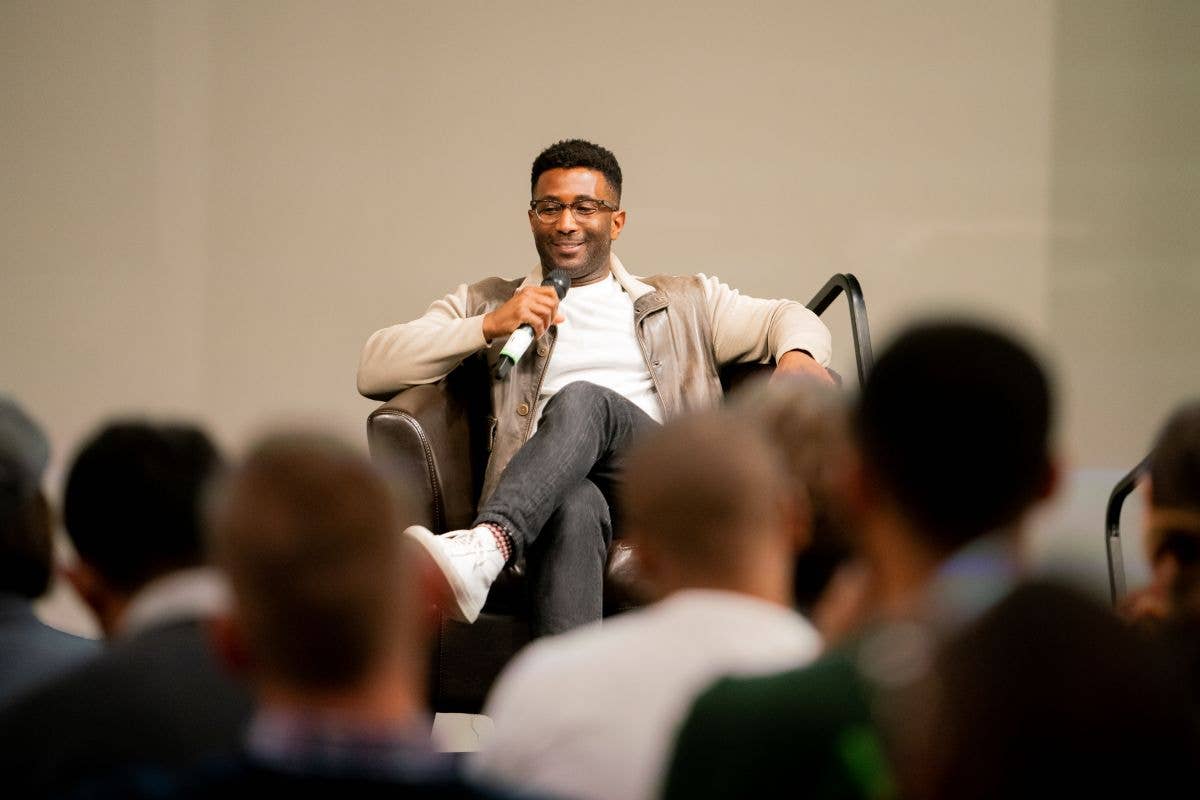 man sitting casually in leather chair on stage giving lecture