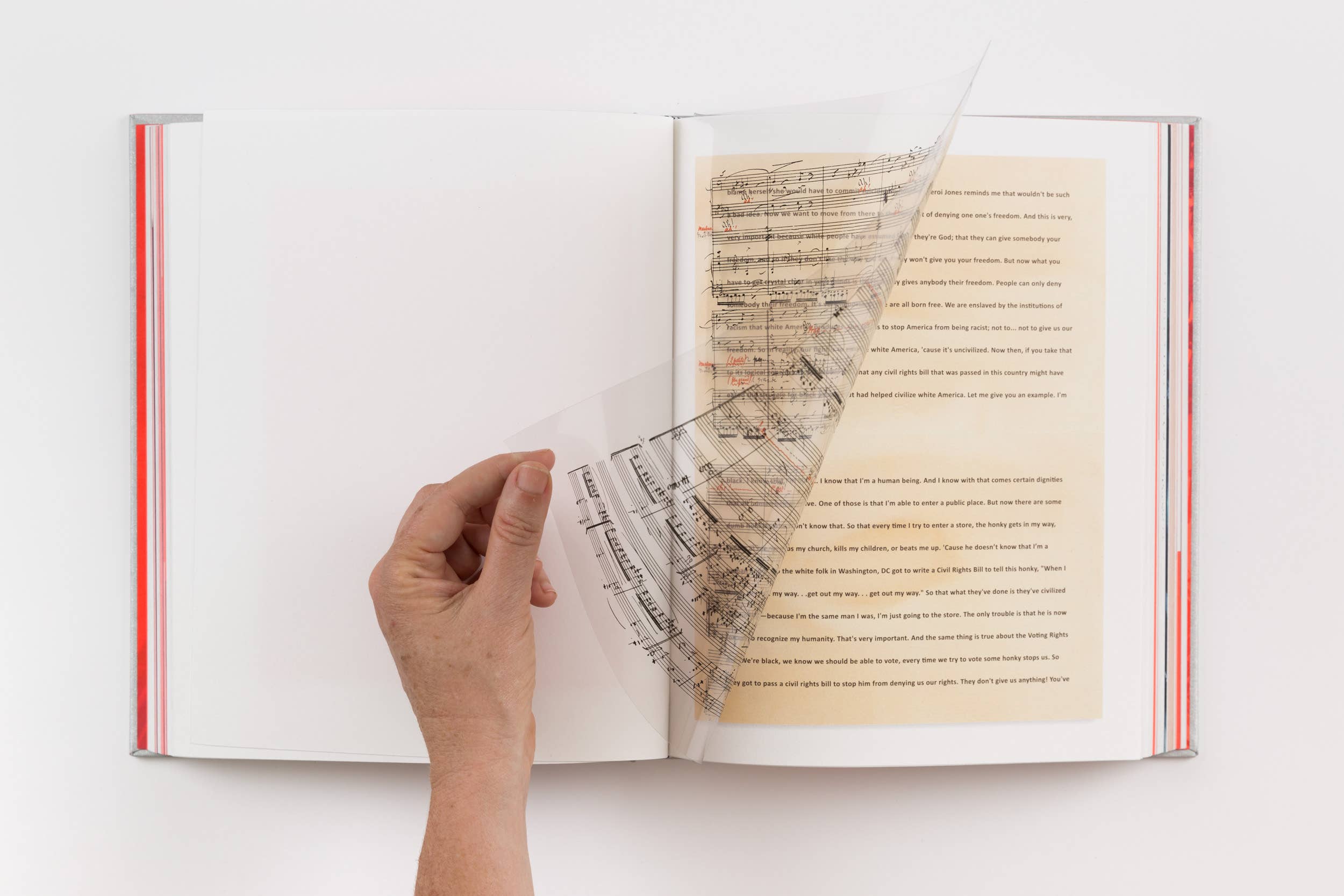 Hand holding a book open to pages with printed text, sheet music and red striped bindings.