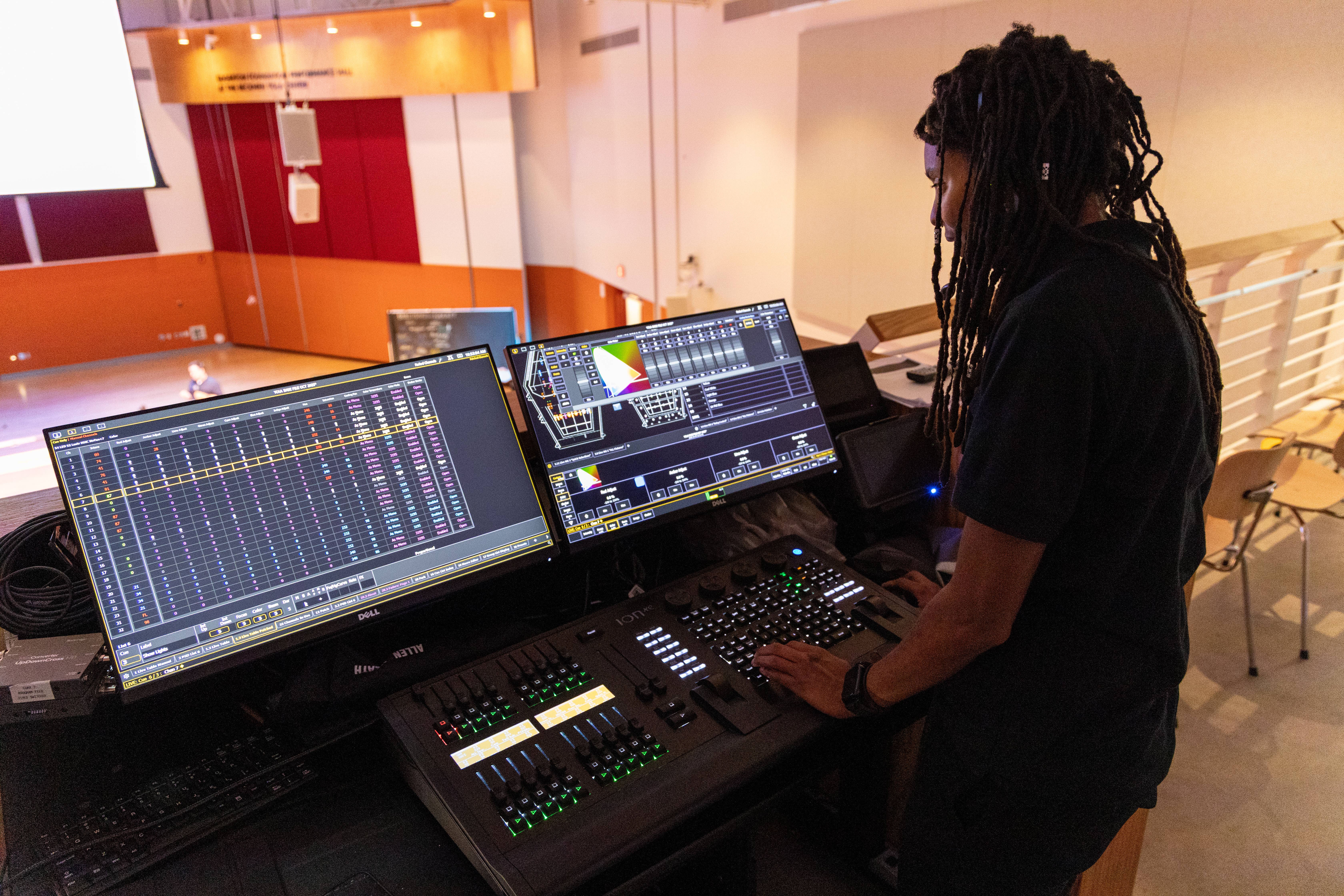 Technician operating a console with multiple screens in an indoor control room.