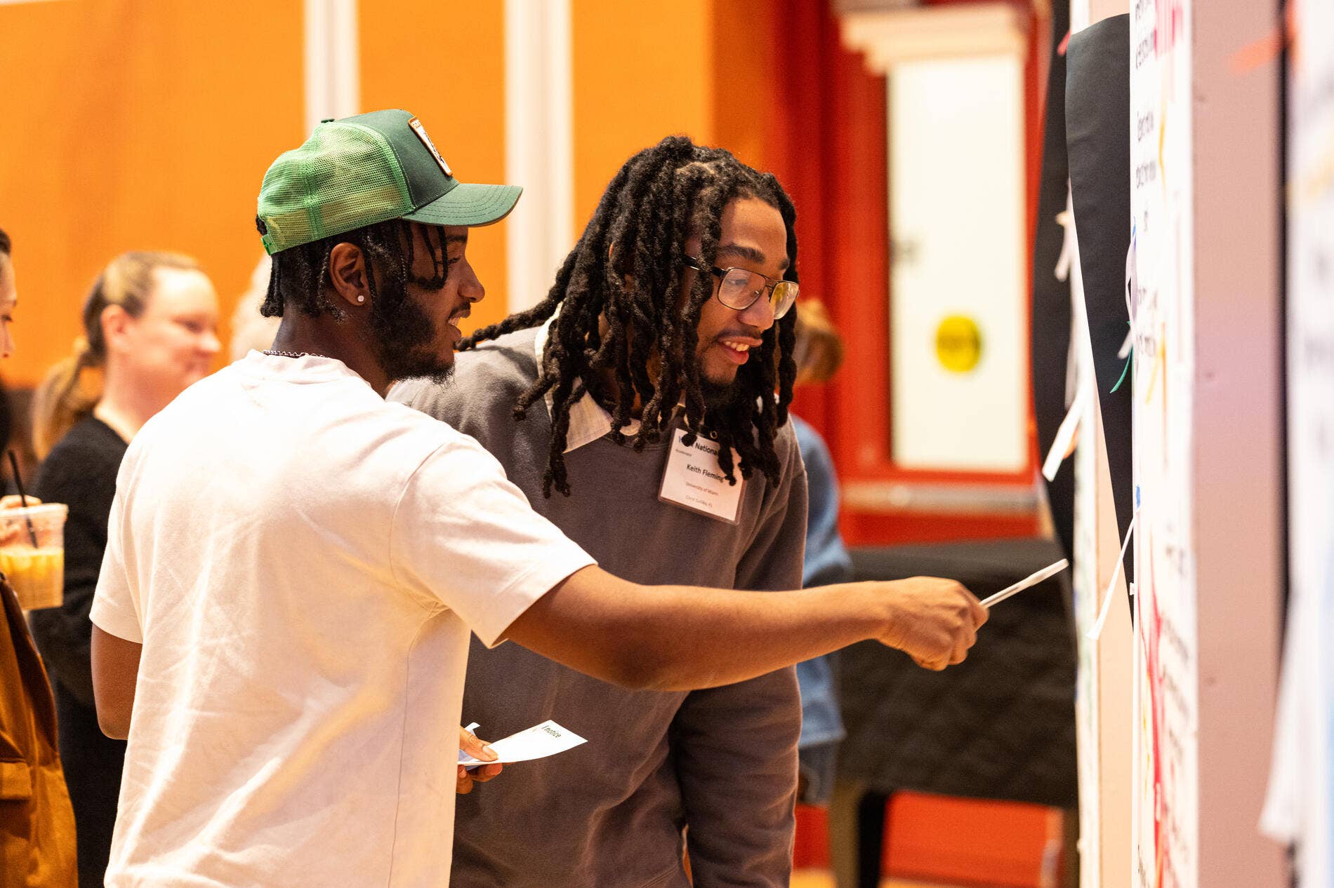 Two people point at a poster board during a conference.
