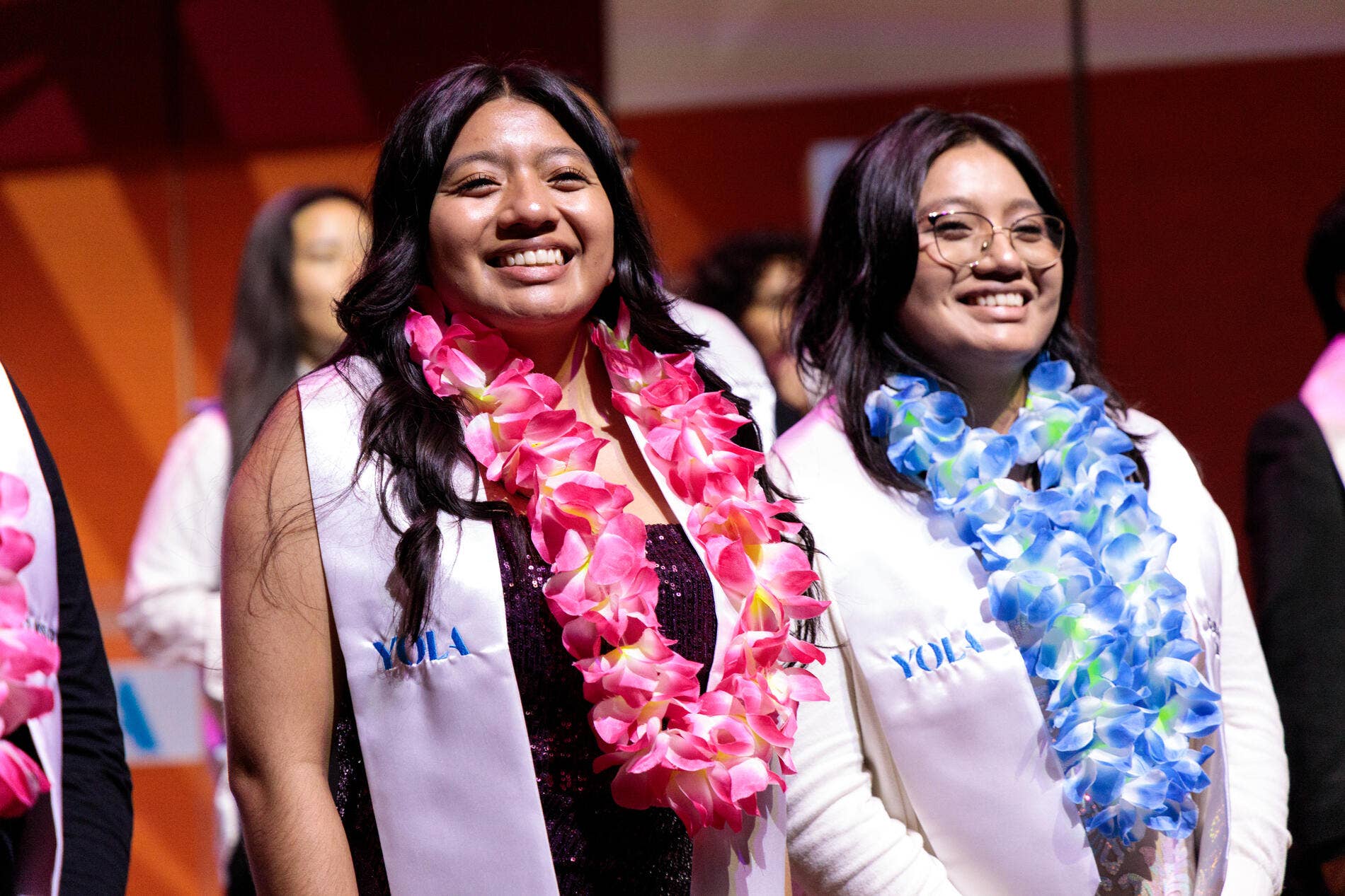 Smiling women wearing leis and a sash that says YOLA.