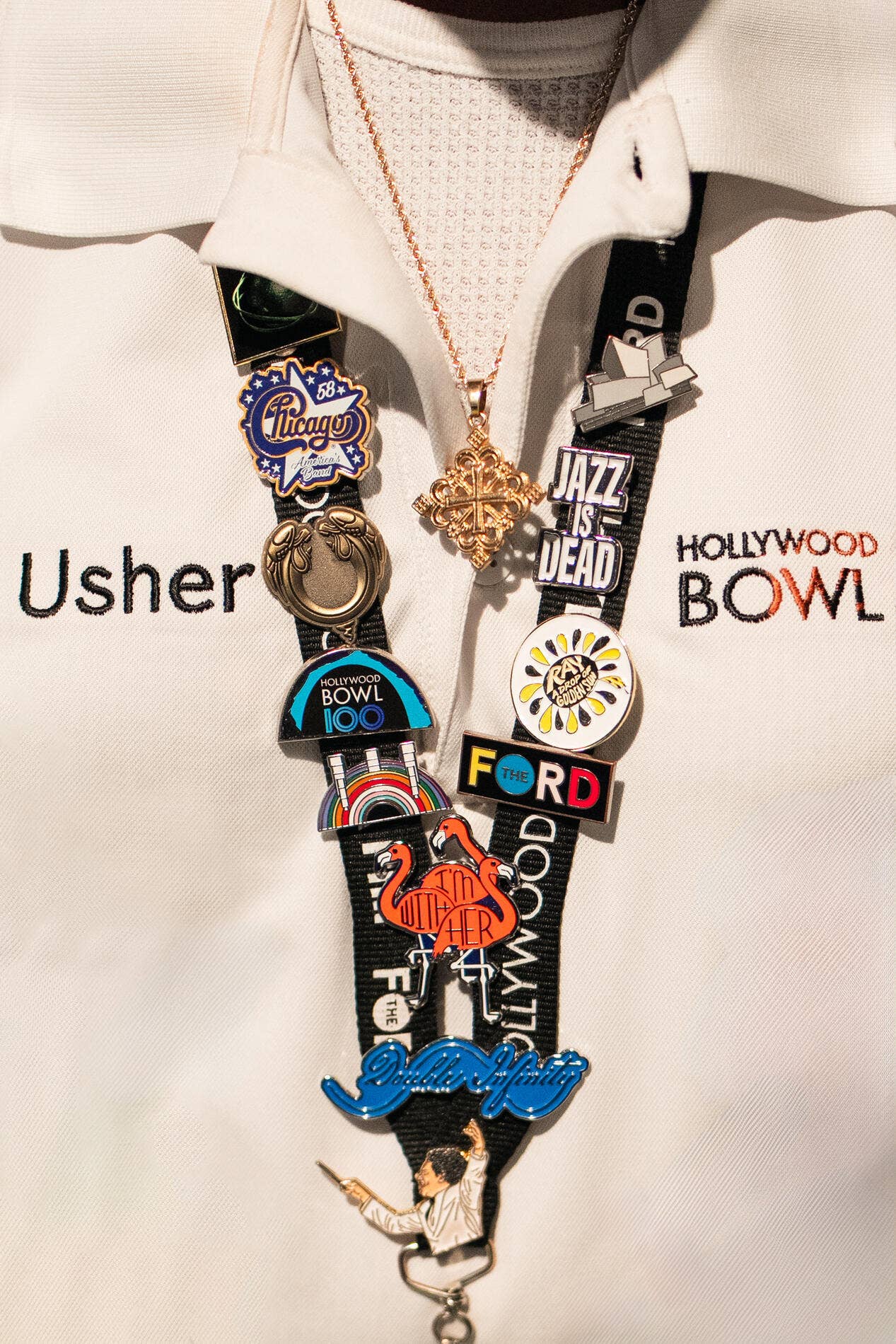 Close-up of a lanyard with multiple travel and landmark pins, including Chicago, Jazz is Dead, and Hollywood Bowl.