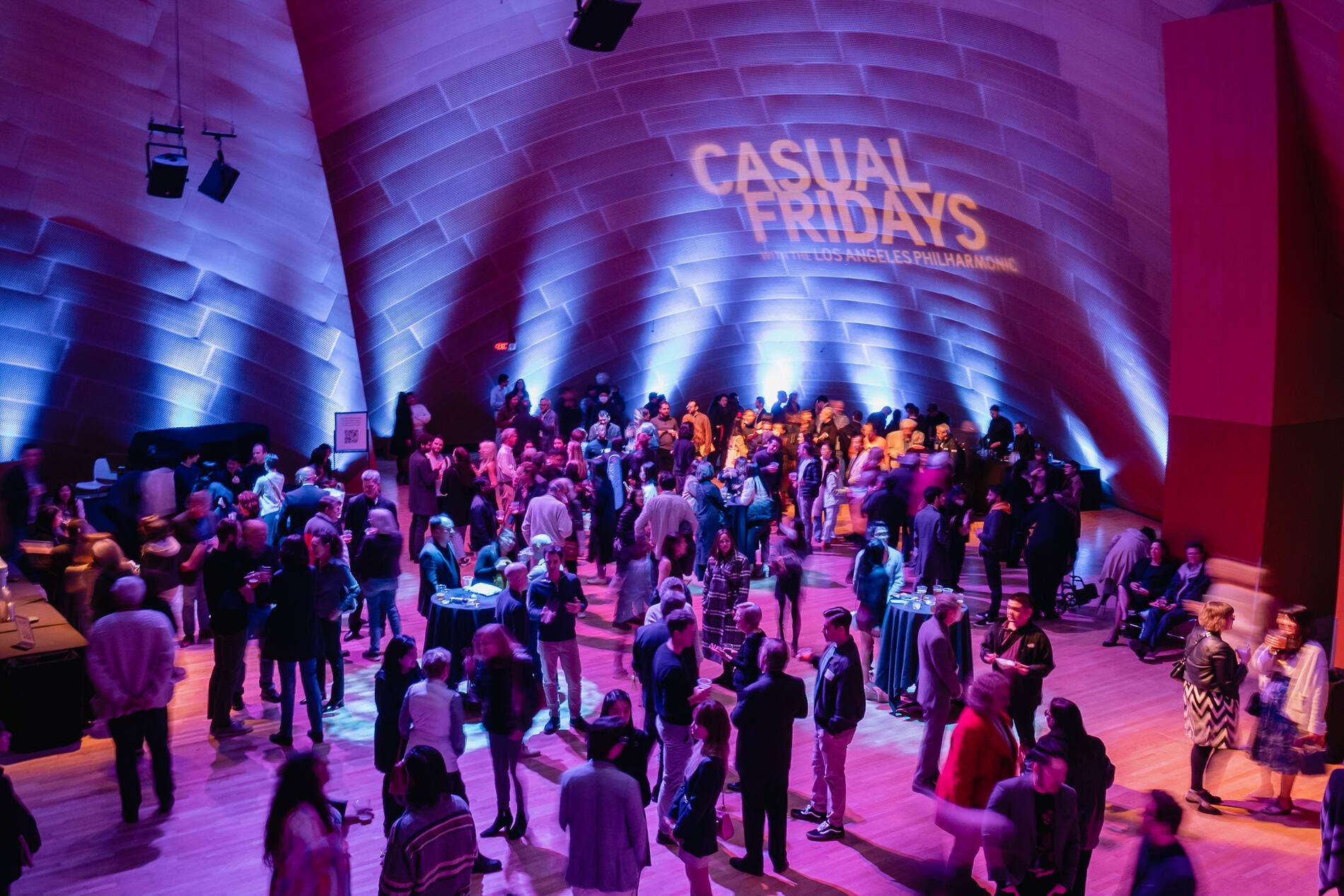 Crowd gathers in a concert hall under purple lighting with “Casual Fridays” banner and LA Philharmonic branding.