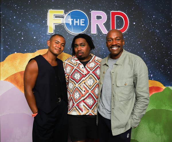 Tres hombres posan delante de un colorido telón de fondo del evento «F the RD».