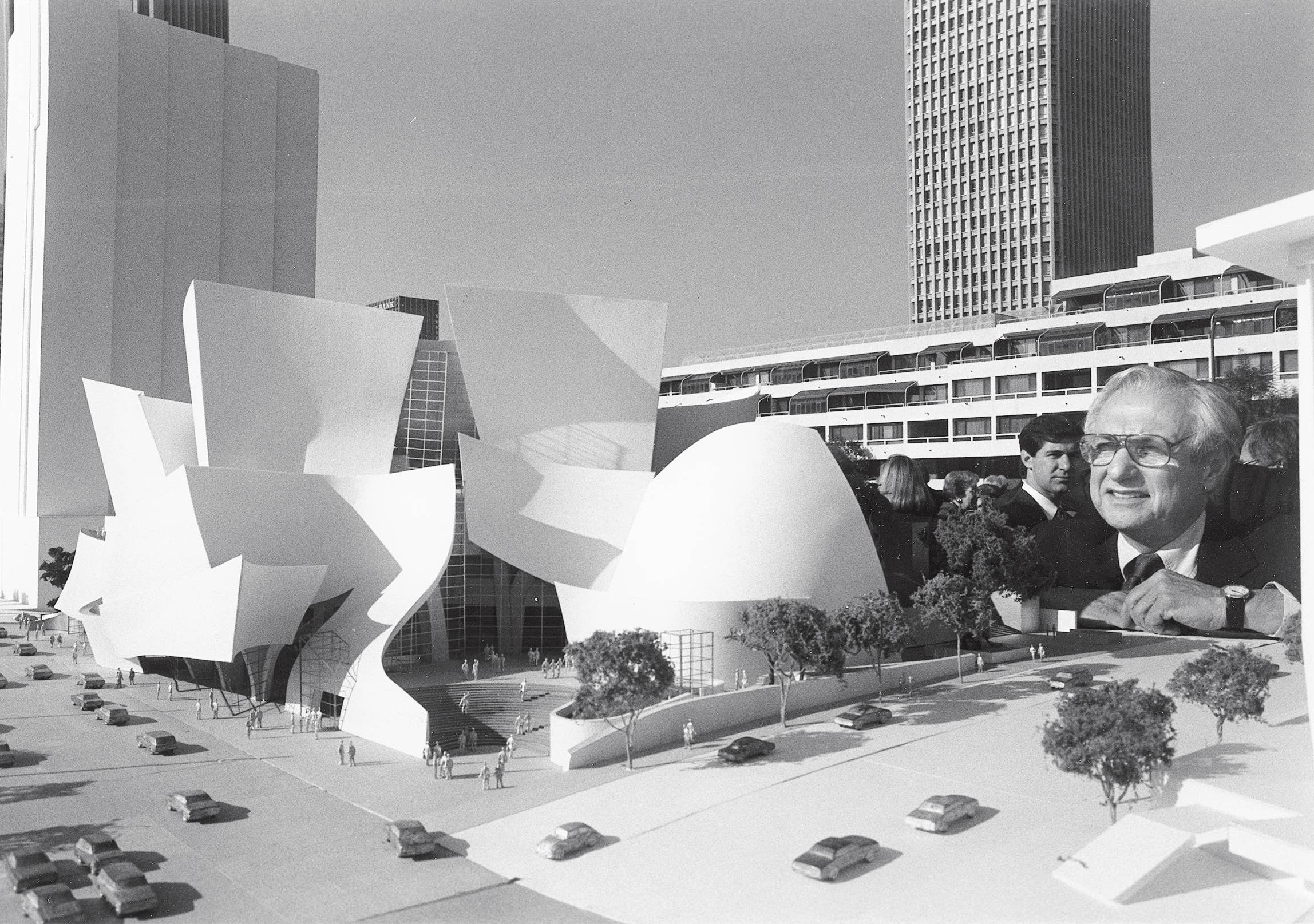 Frank Gehry smiling in suit in foreground beside WDCH model.