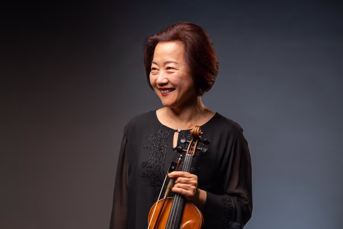 Bing Wang poses for a studio portrait while holding her violin.