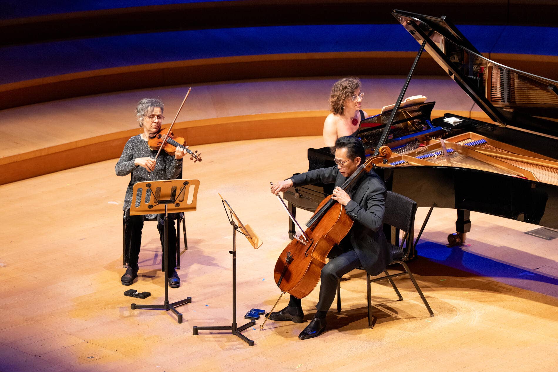 Varty Monouelian tocando el violín junto a otros dos músicos en el escenario 