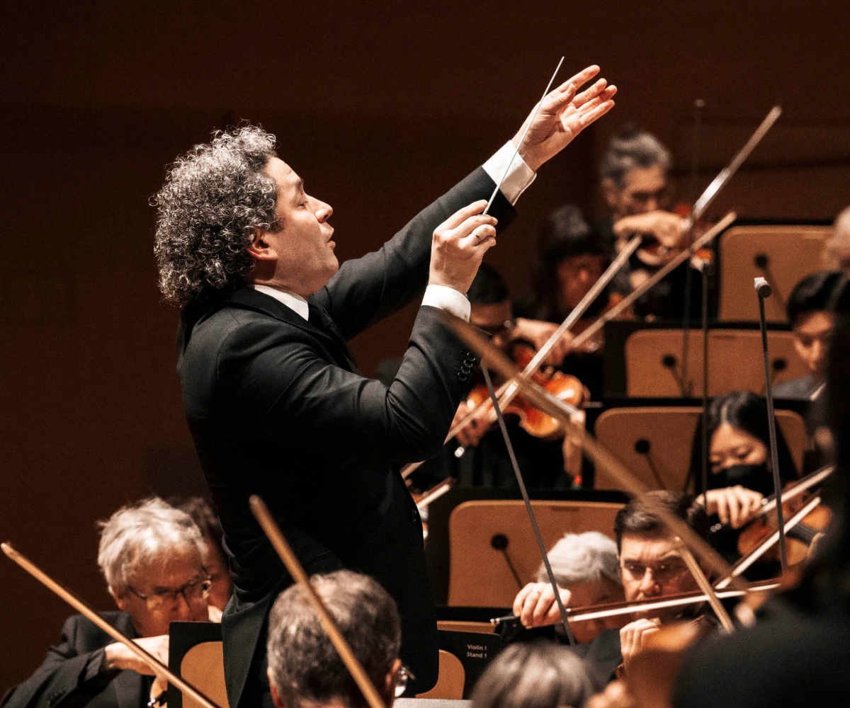 Gustavo Dudamel conducting with his hands raised holding a baton. 