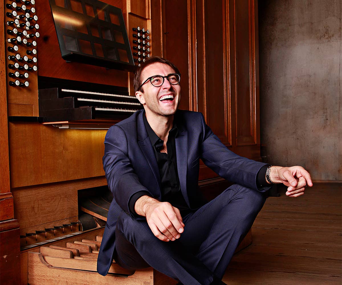 Christian Schmitt smiles, sitting in front of an organ. 