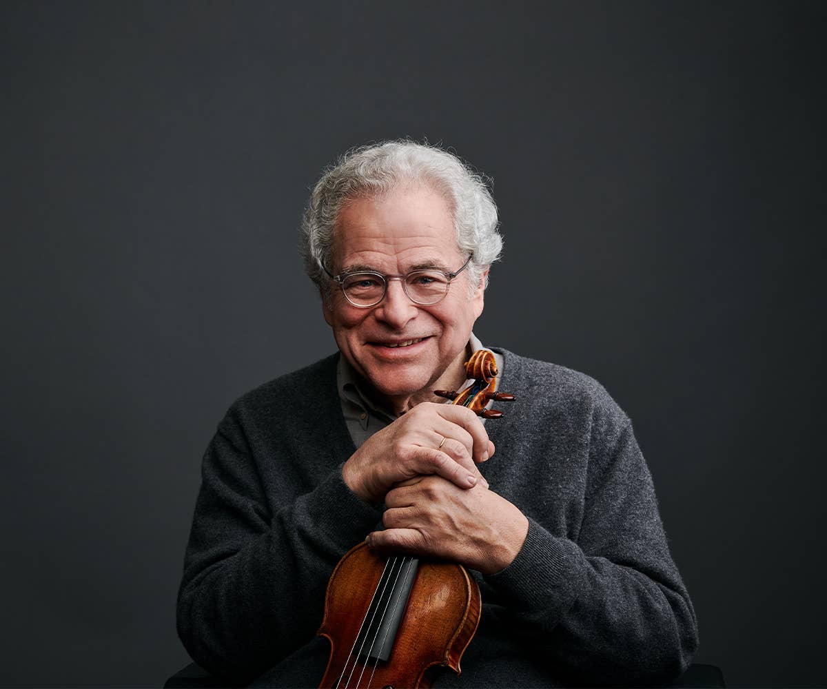 Close up of Itzhak Perlman smiling and holding a violin. 