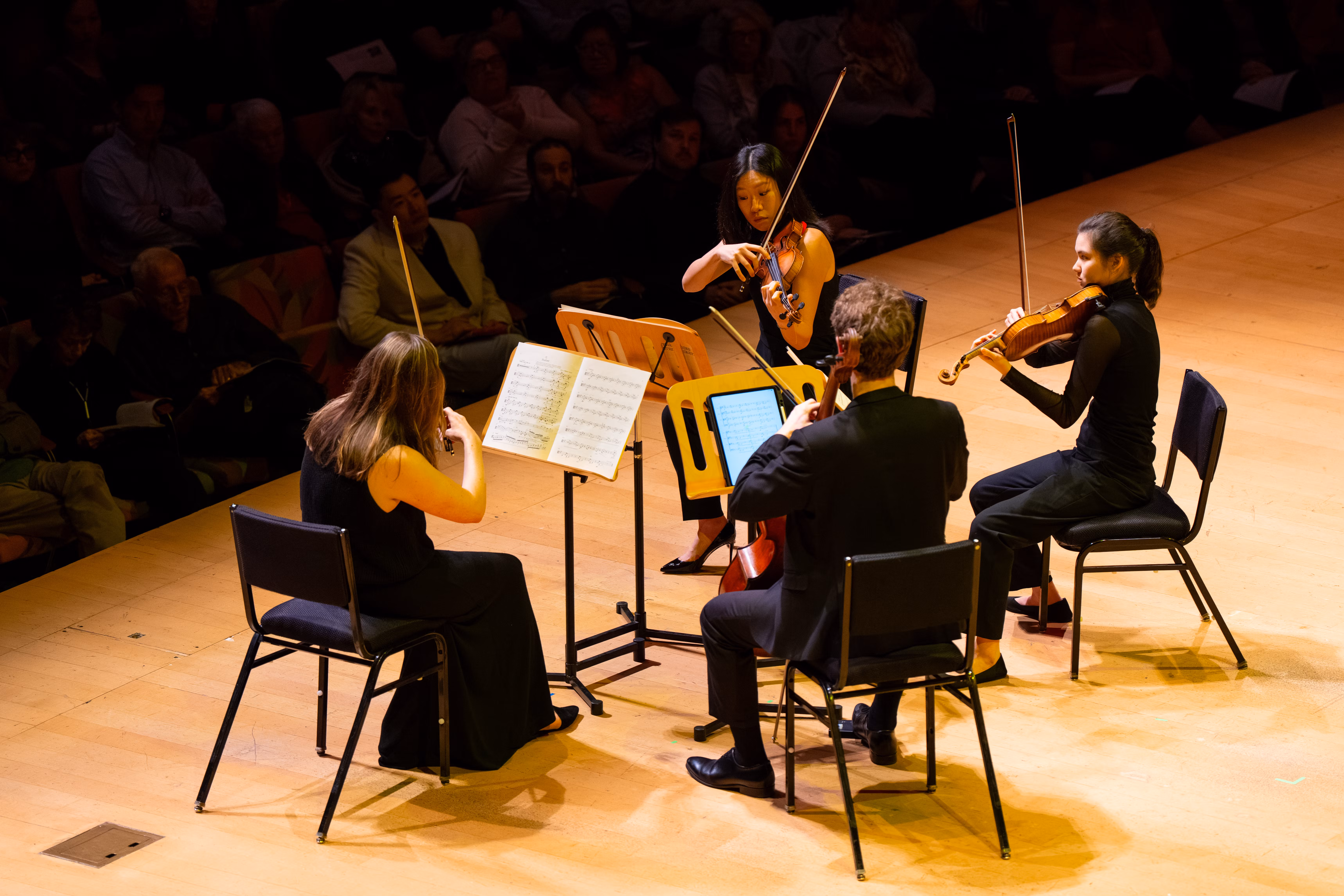 four violinists performing on concert hall stage
