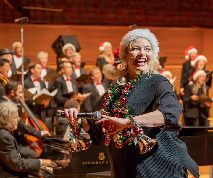 Woman in santa hat with microphone at festive holiday concert