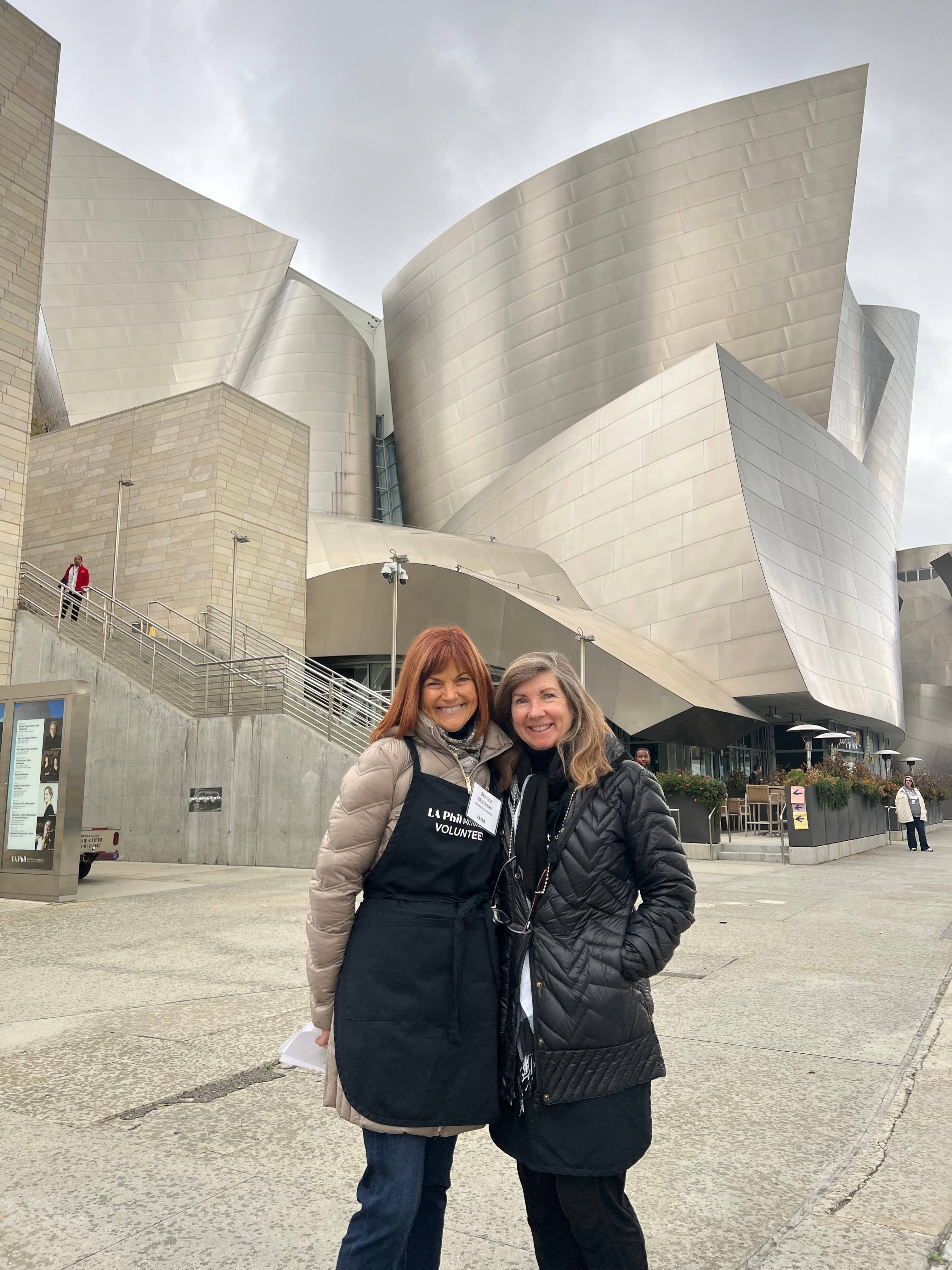 dos mujeres con delantal posando delante de un edificio moderno
