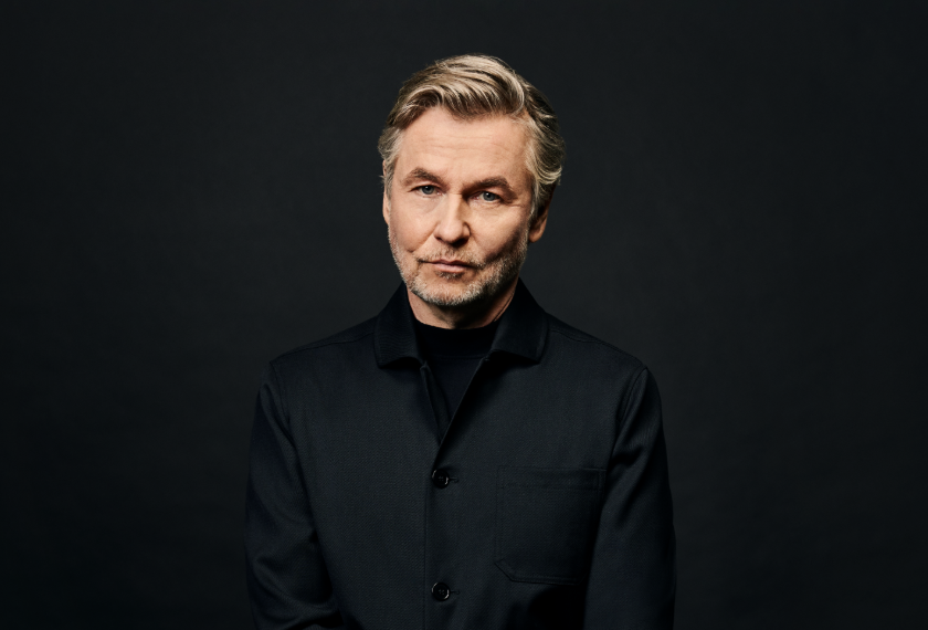Esa-Pekka Salonen sits in a dark jacket against a dark studio background.