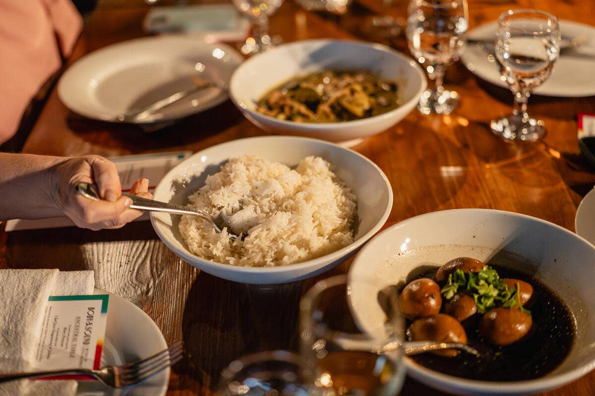 An ancestral table of rice and vegetables at a warmly lit table with sparkling drinks.