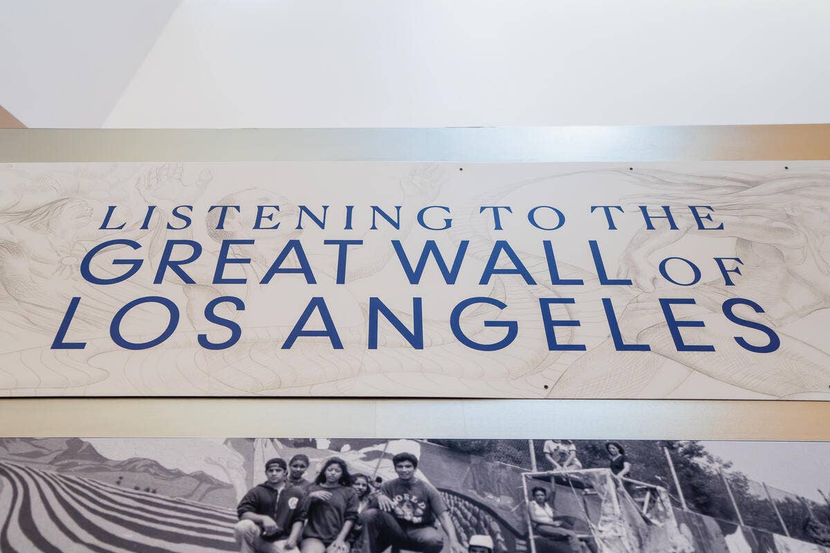 Banner on white wall reading “Listening to the Great Wall of Los Angeles” above black-and-white photos