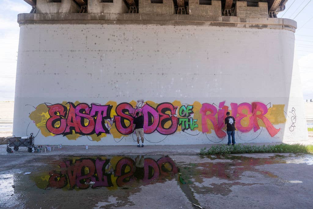 People painting the pink, green, and yellow text 