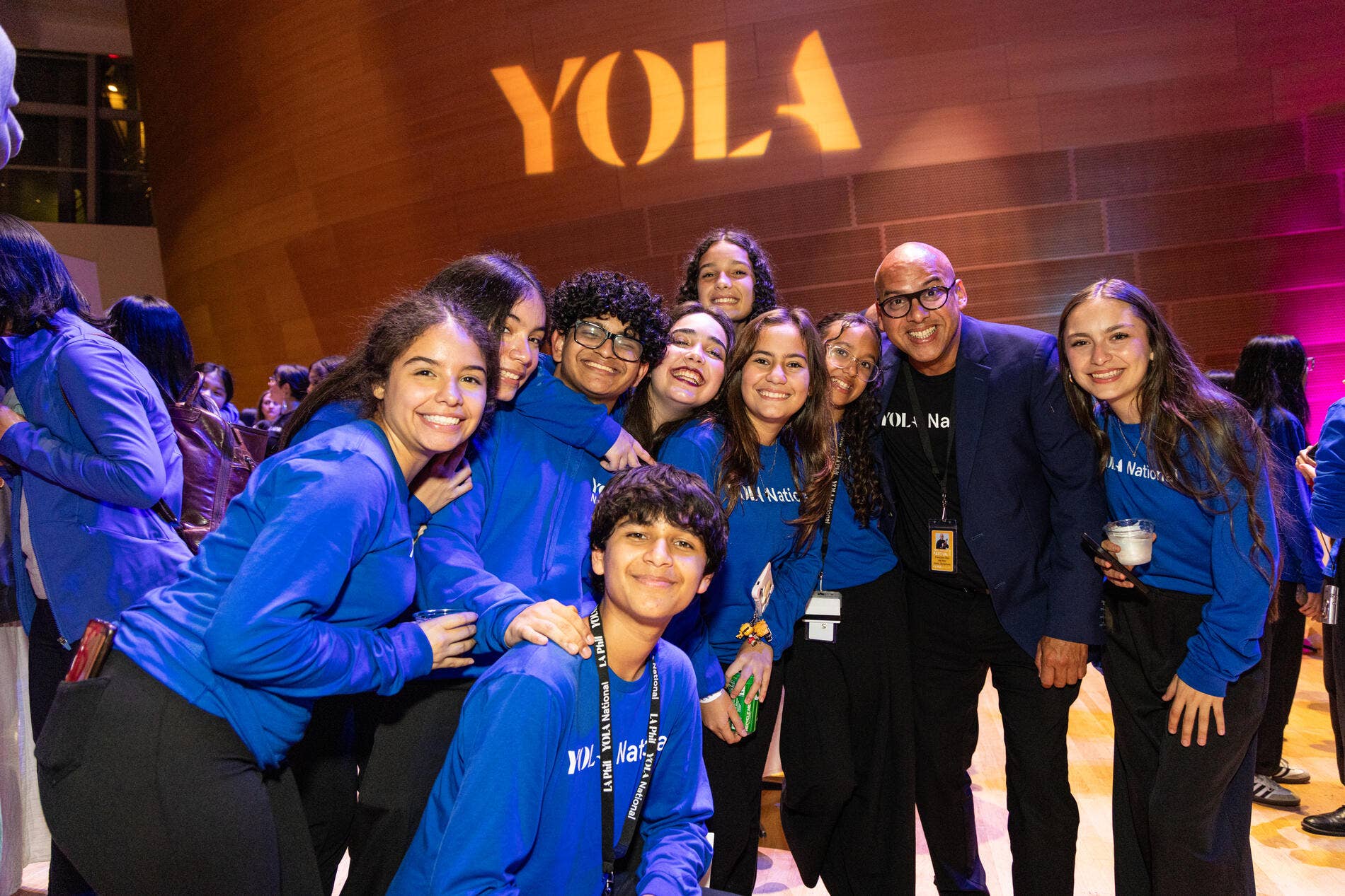 Group of student musicians in blue YOLA National Festival shirts in the Walt Disney Concert Hall, with 