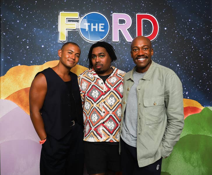 Three men pose in front of a colorful “F the RD” event backdrop.