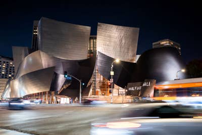 Night view of modern curved courthouse with street traffic light trails and illuminated signage near downtown.