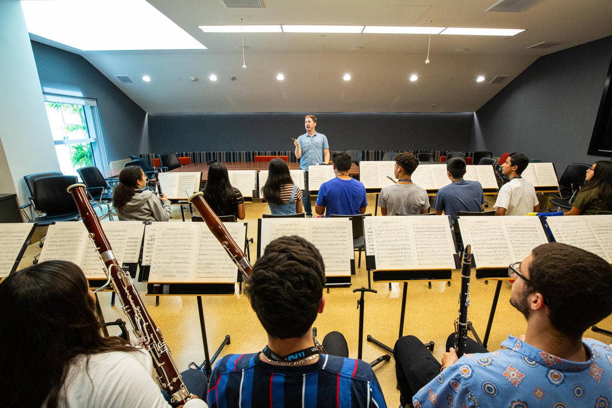 A YOLA National teaching artist stands at the front of students during rehearsal.