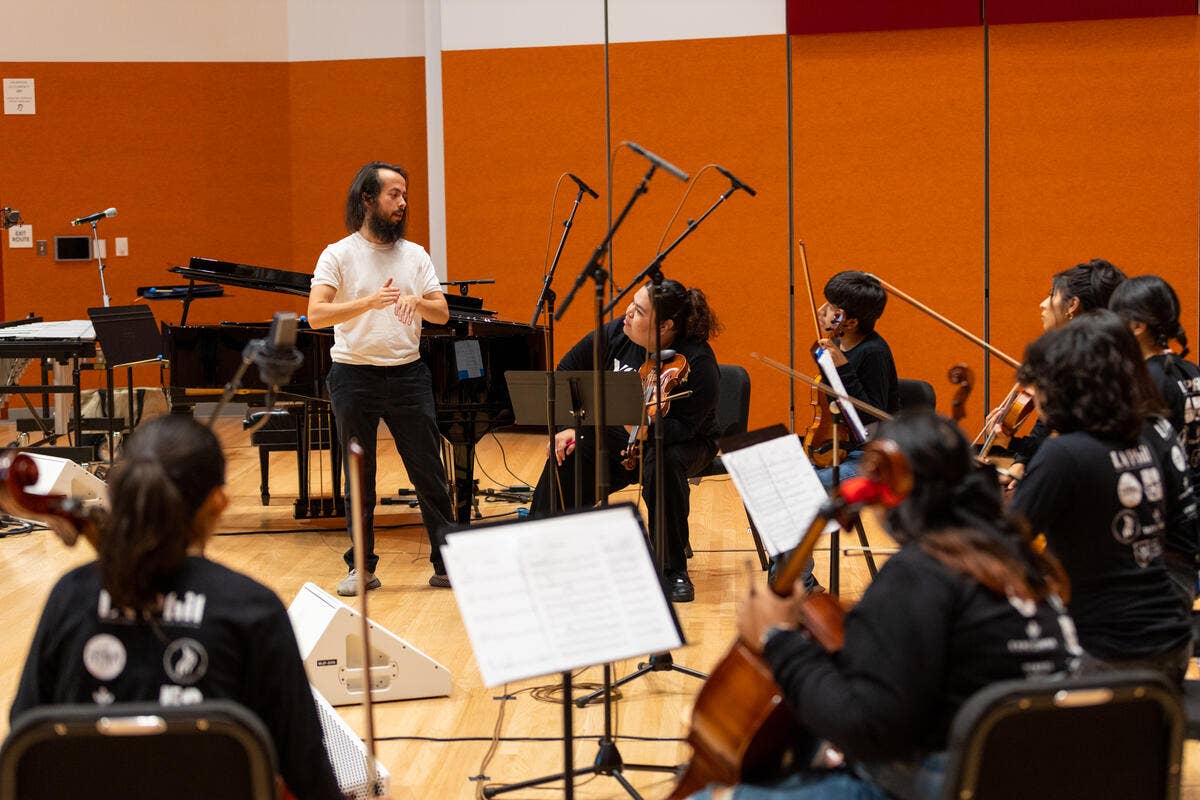 A YOLA alumni instructs YOLA students during rehearsal. 