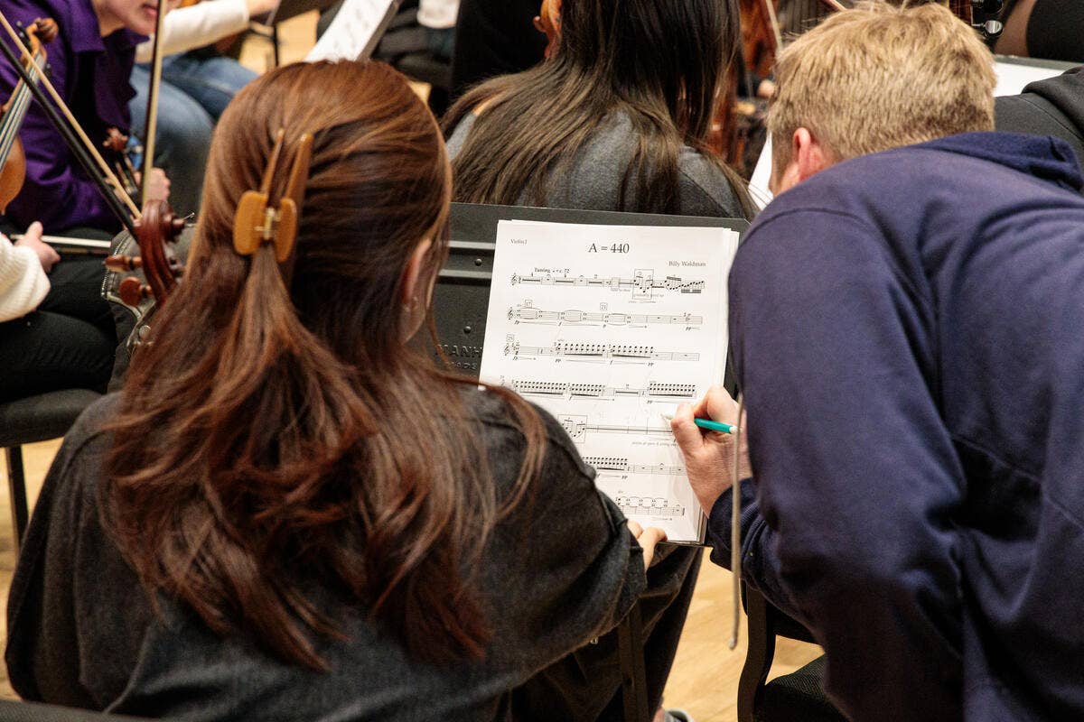 A YOLA student reviews sheet music during a Composer Fellowship Program rehearsal.