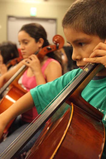 A young YOLA student plays the cello during rehearsal at the Expo Center Hub location. 