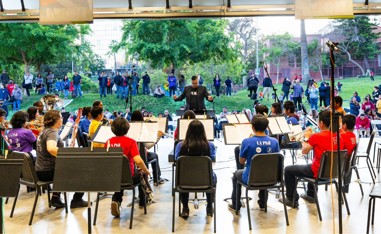 YOLA at HOLA students perform on stage at an outdoor venue. 