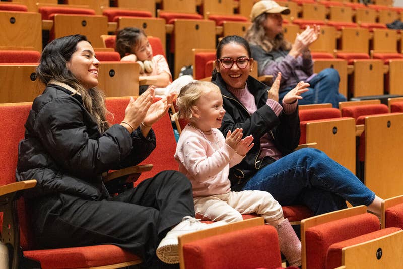 YOLA student's family members enthusiastically cheer them on from the audience inside the Beckmen YOLA Center.