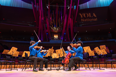 A conductor leads YOLA Institute students during a concert performance.