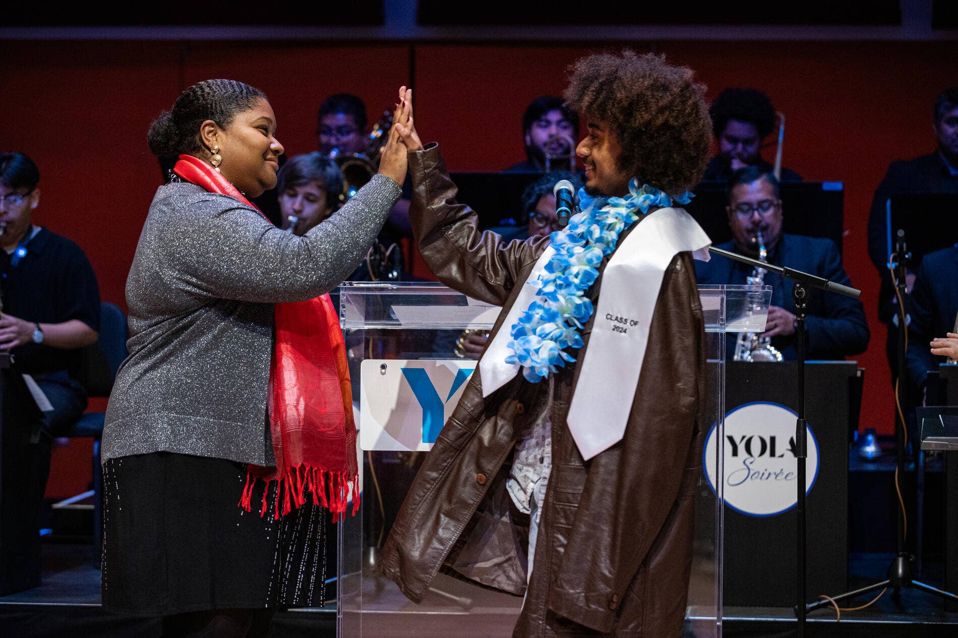 A YOLA graduate high-fives on stage during their graduation walk on stage. 