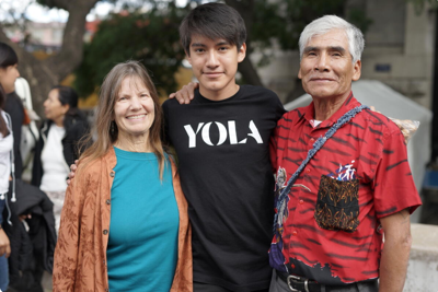 A YOLA student poses with their family for a photo during an outdoor event.