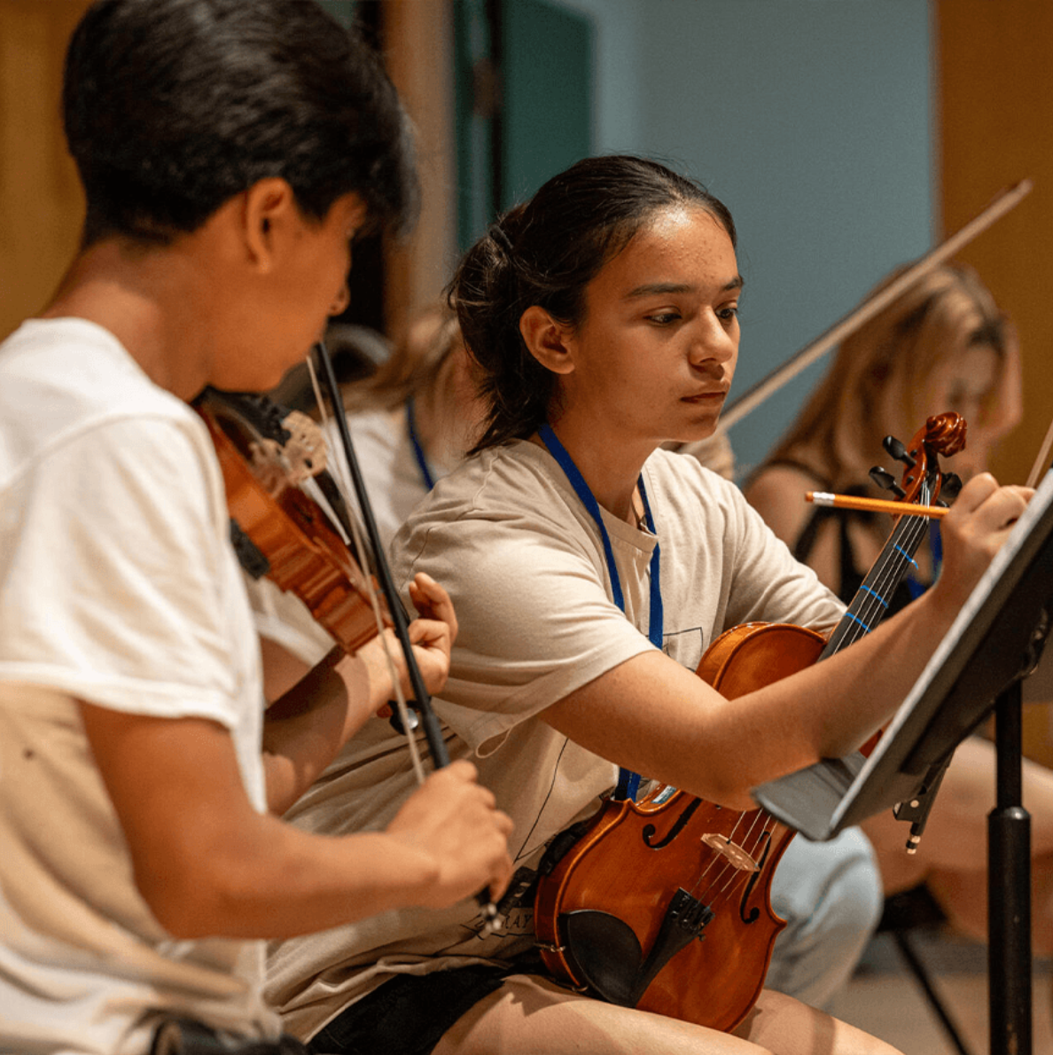 A YOLA student takes notes in her score during rehearsal.
