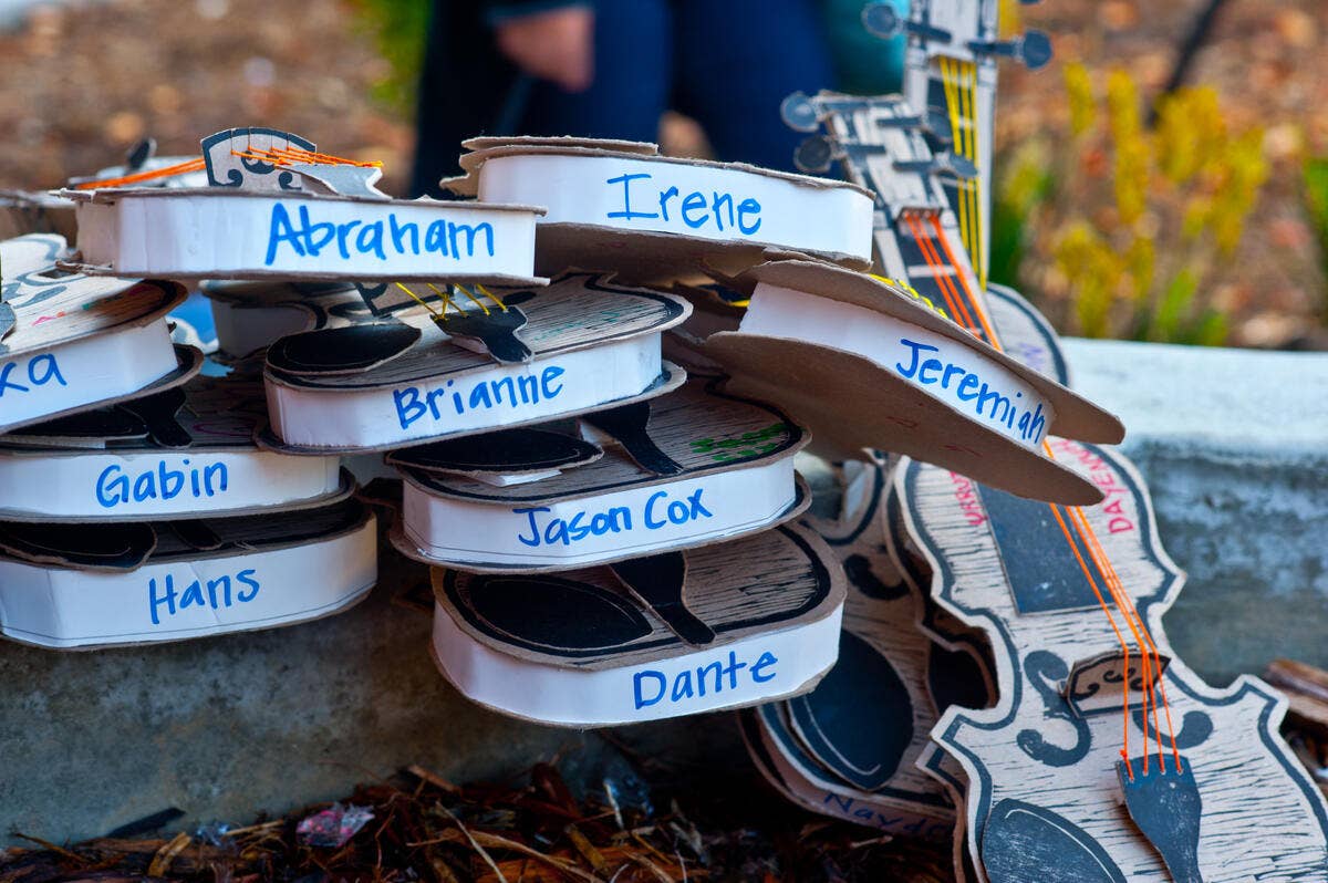 Stacked practice violins made of cardboard and string.
