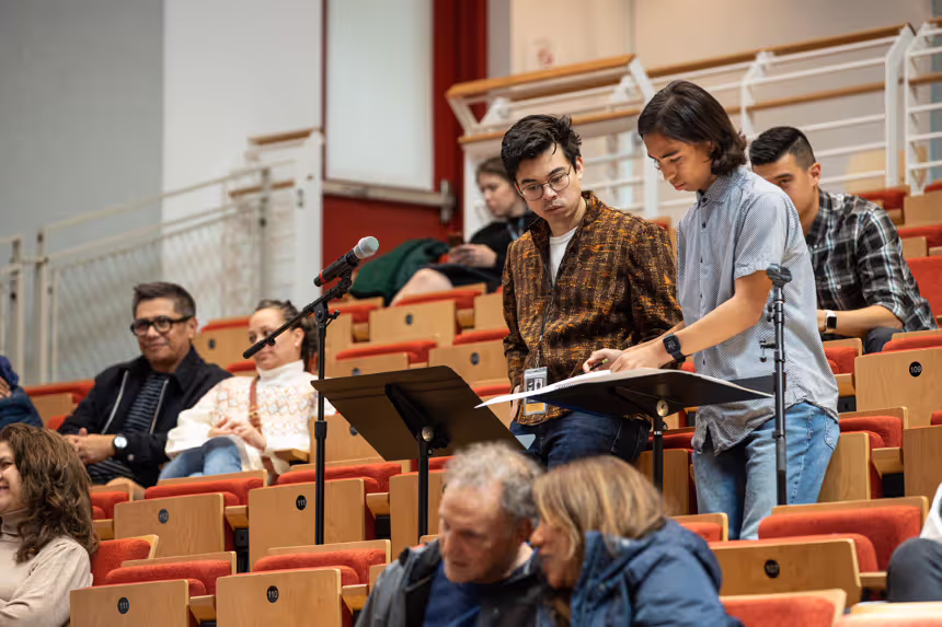Two young composers reading sheet music.