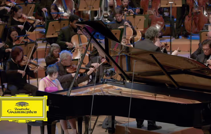 woman playing piano in front of orchestra
