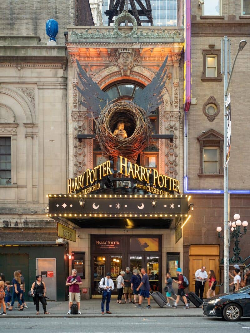 Harry Potter and the Cursed Child theater entrance with people outside on a city street