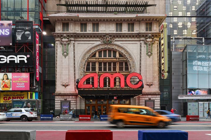Facade of the AMC Empire 25 with a yellow cab on the street driving by.