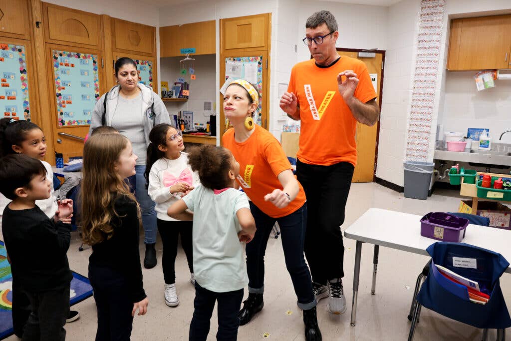 Teaching artists playing around with children in a classroom.