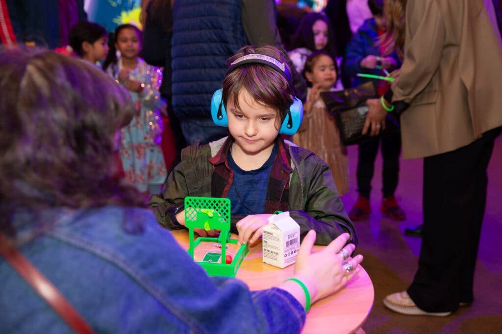 A child wearing ear defenders and doing an activity.