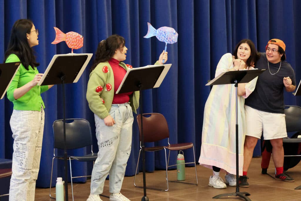 4 performers standing up with two holding a fish puppet.